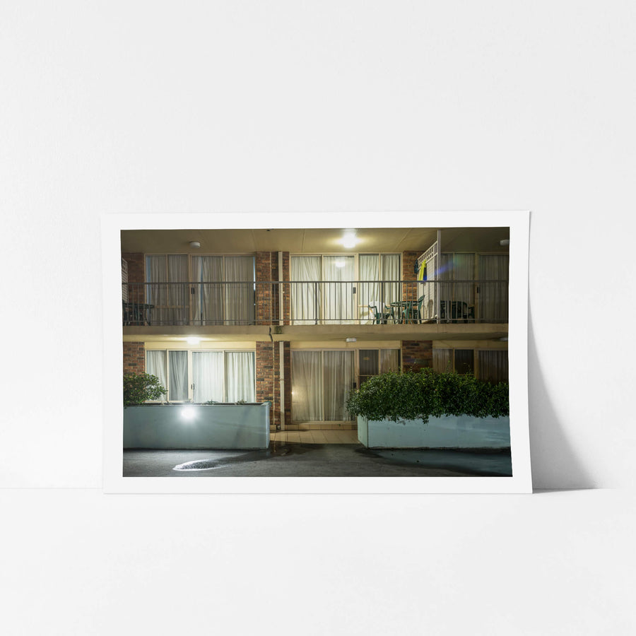 The Beachcomber Motel at Hotel Motel 101, two storeys of brown brick and concrete planter boxes face the carpark.