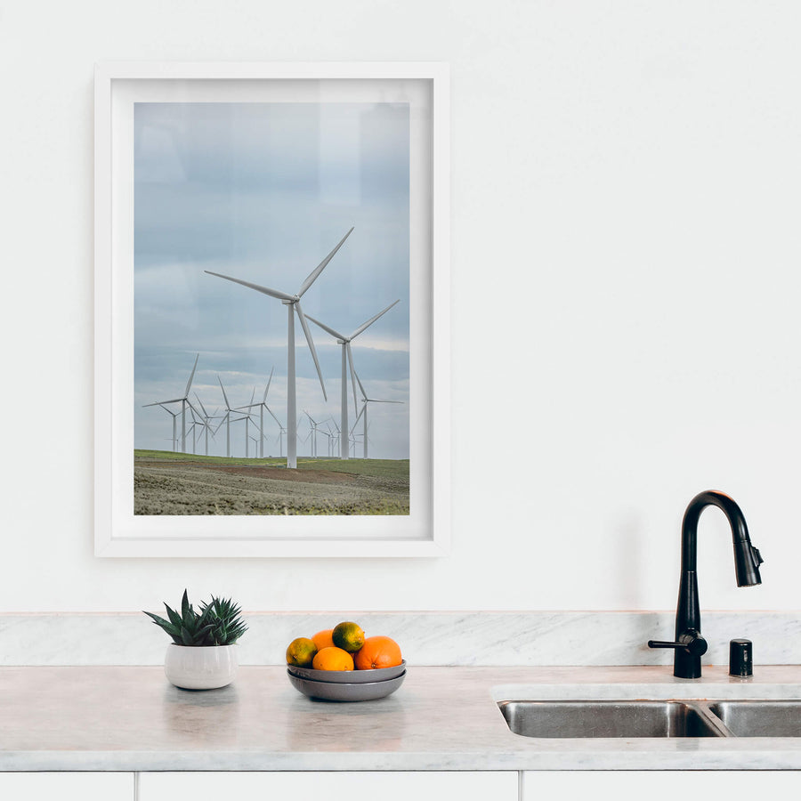Cluster at Landscapes, white steel towers rise from low, green-brown pastureland under a flat grey sky.