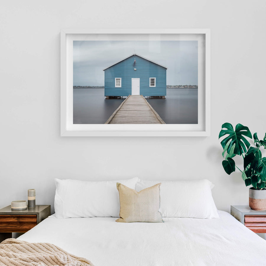 Crawley Edge Boatshed at Landscapes, a single blue timber boatshed sits on steel piles over flat grey water.