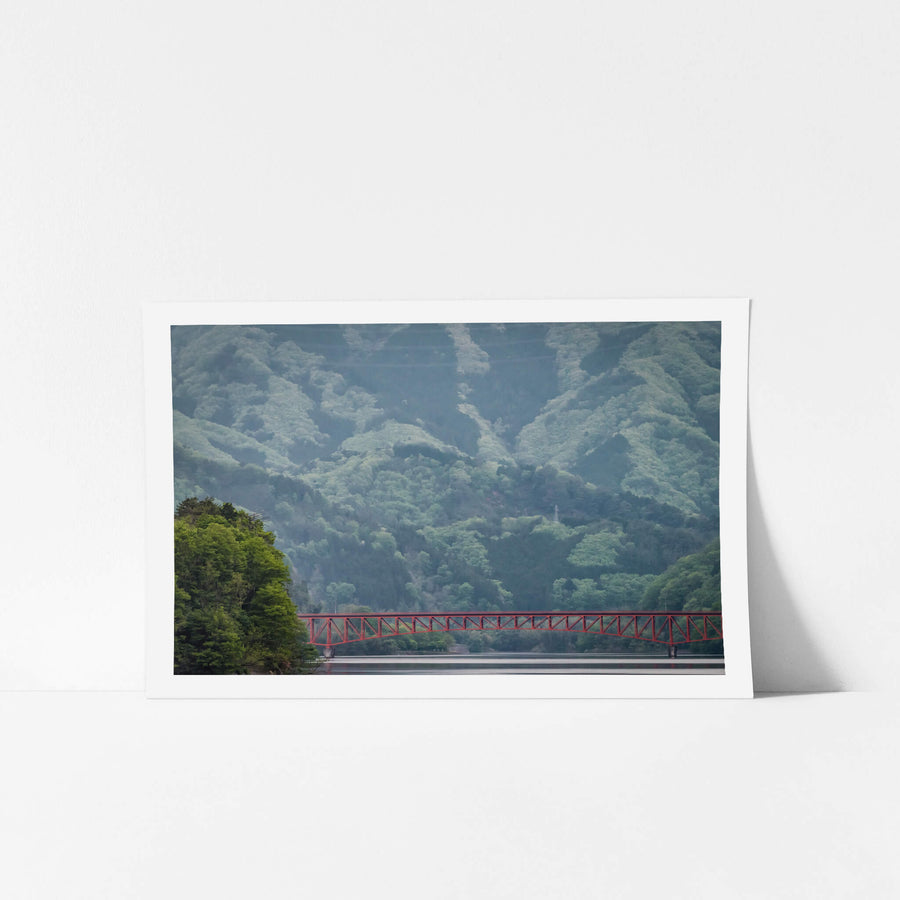 Kusaki Dam Lake at Landscapes, a red steel bridge dwarfed by mountains stretches over a lake.