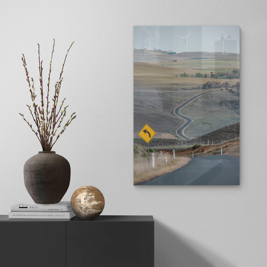 The Snowy River Way at Landscapes, a single lane of asphalt cuts through open grazing country, snaking down into a valley.