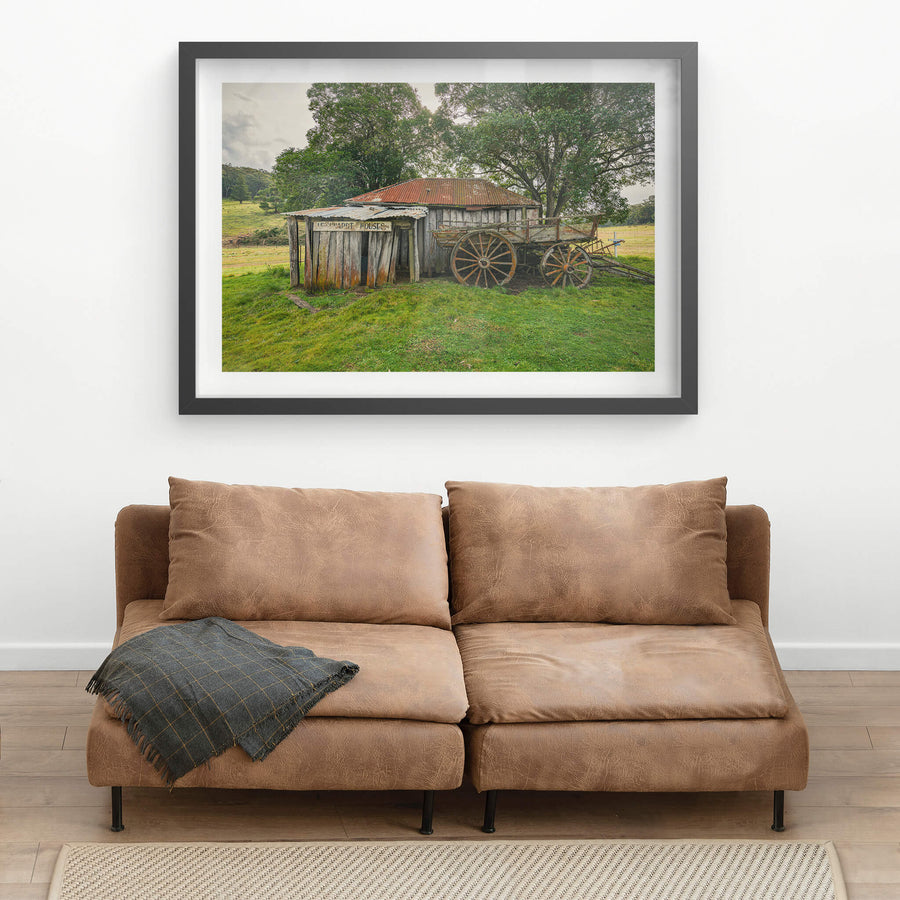 Backyard at Leichhardt House, a weathered timber slab building sits low in green pasture.