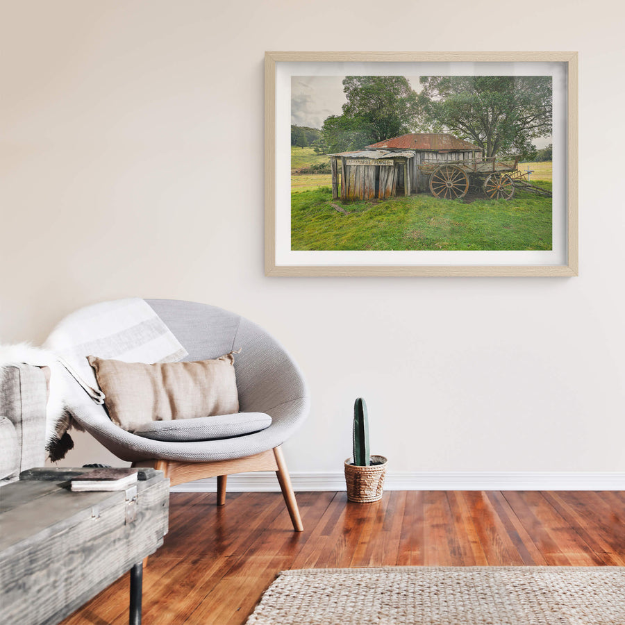 Backyard at Leichhardt House, a weathered timber slab building sits low in green pasture.