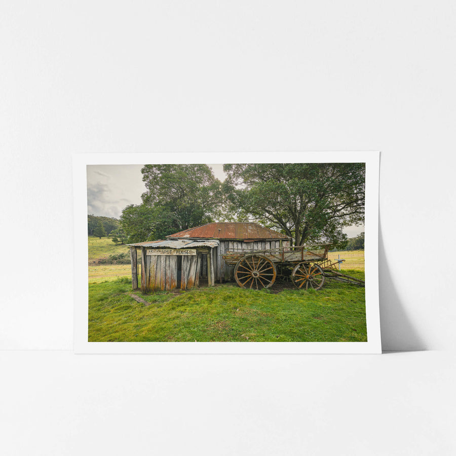Backyard at Leichhardt House, a weathered timber slab building sits low in green pasture.
