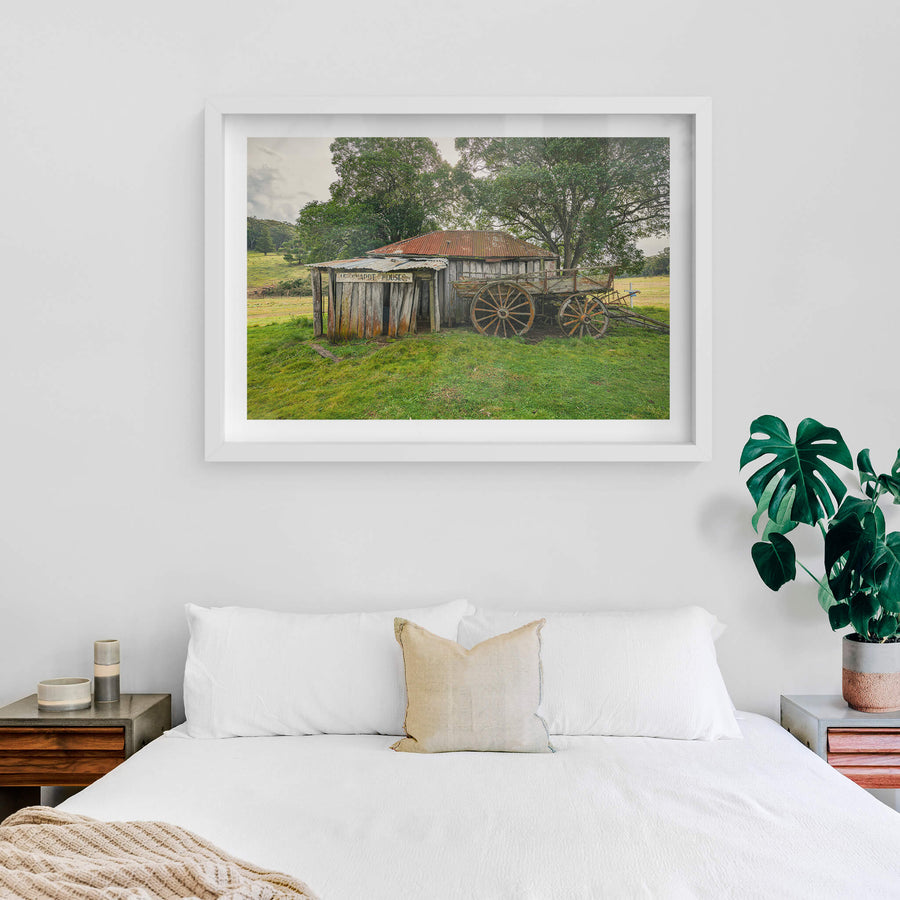 Backyard at Leichhardt House, a weathered timber slab building sits low in green pasture.