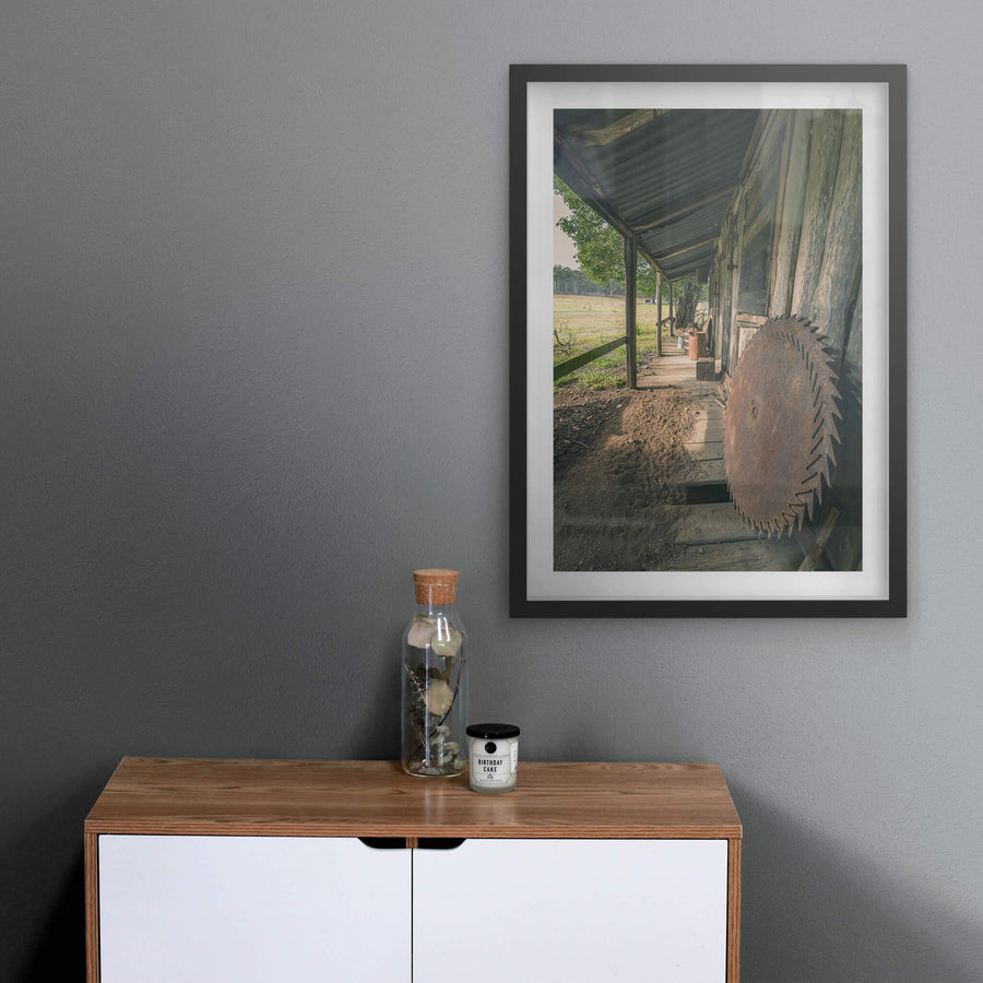 Porch Saws at Leichhardt House, a large circular saw blade leans against weathered timber cladding on a narrow verandah.