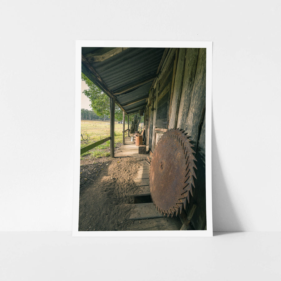 Porch Saws at Leichhardt House, a large circular saw blade leans against weathered timber cladding on a narrow verandah.
