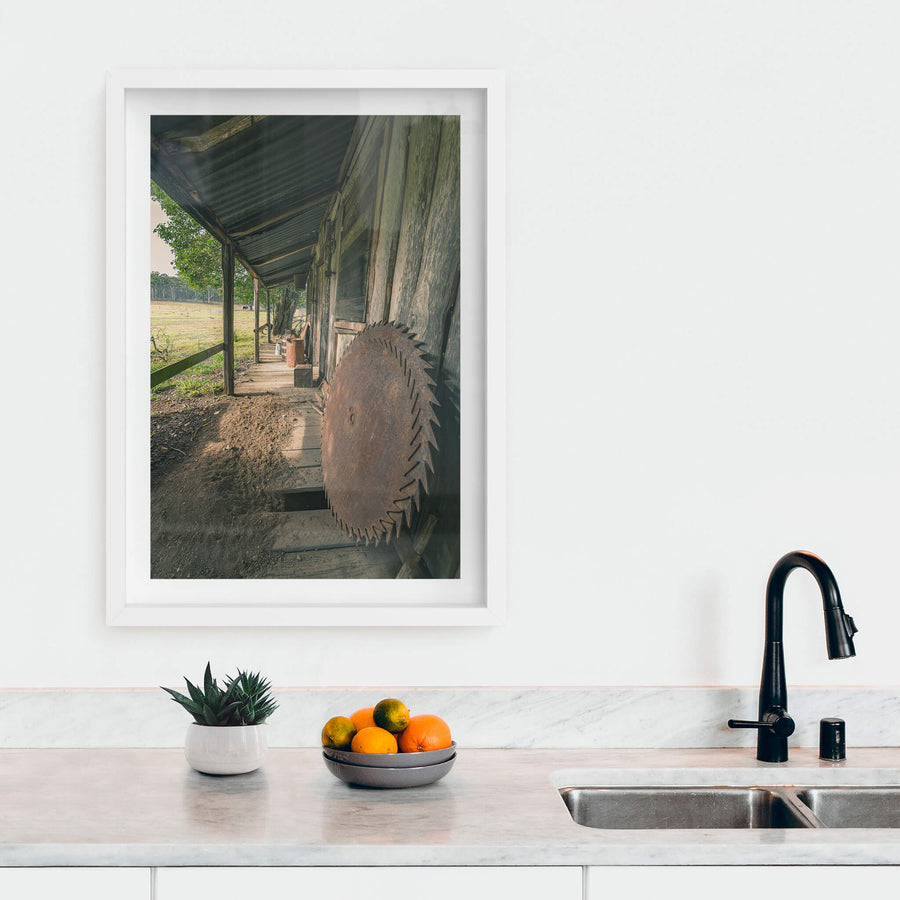 Porch Saws at Leichhardt House, a large circular saw blade leans against weathered timber cladding on a narrow verandah.