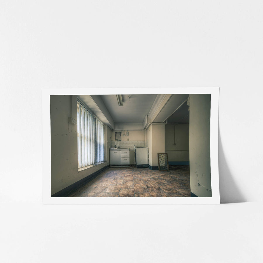 Nurses Kitchen at Lewisham Hospital, daylight pushes through vertical blinds, casting long pale strips across vinyl floor.