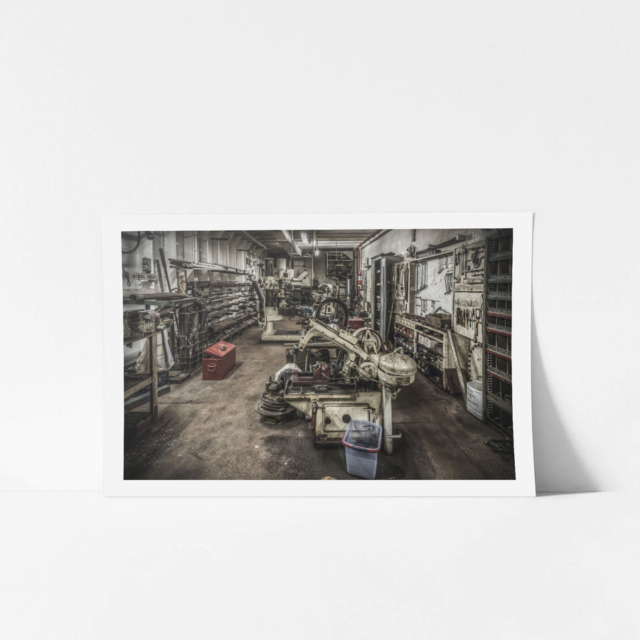 Machine Shop at MV Cape Don, a horizontal bandsaw sits centre-floor, its blade guard and drive wheel coated in pale grime.