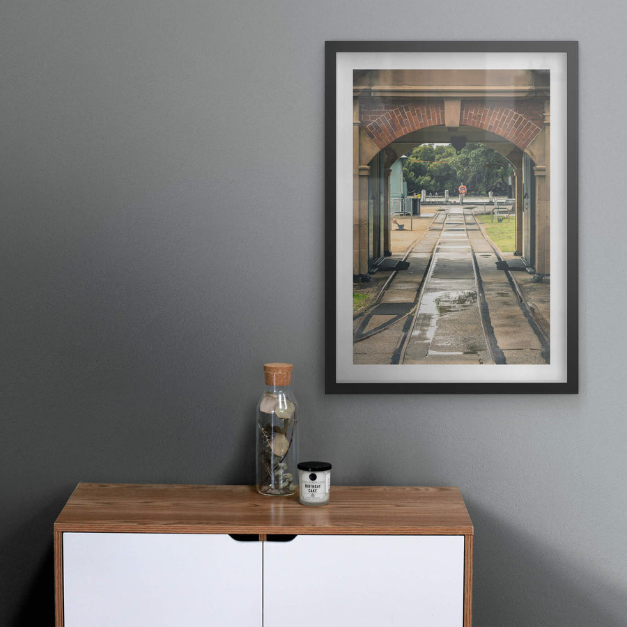 Entrance Rails at Newington Armory, narrow-gauge rail tracks run wet through a sandstone and brick archway, heading.
