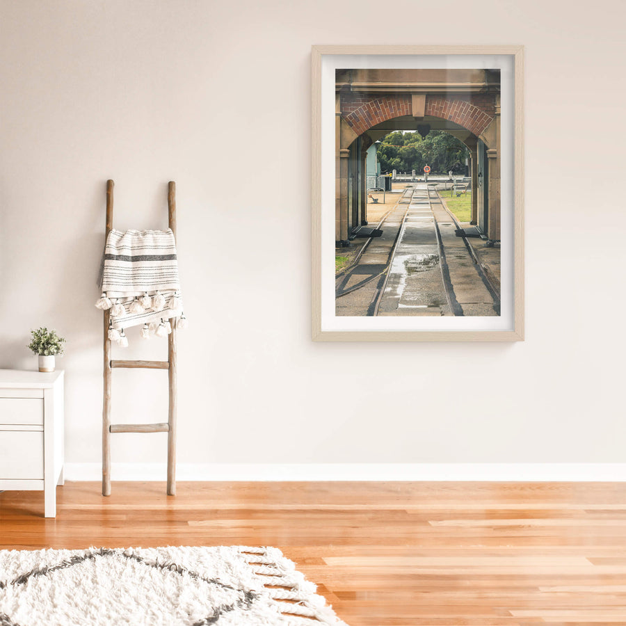Entrance Rails at Newington Armory, narrow-gauge rail tracks run wet through a sandstone and brick archway, heading.