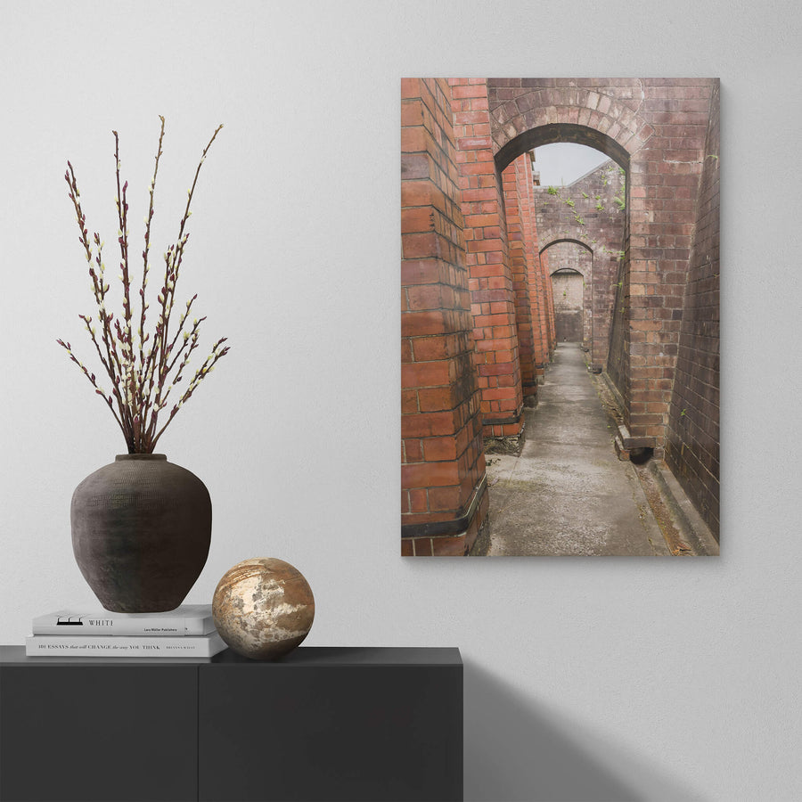 Magazine Exterior Path at Newington Armory, a narrow concrete path runs between two massive brick walls.