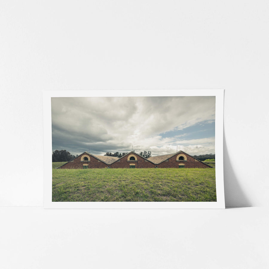 Magazine Roof at Newington Armory, three sawtooth rooflines rise from an earth embankment, red brick gables barely clearing.