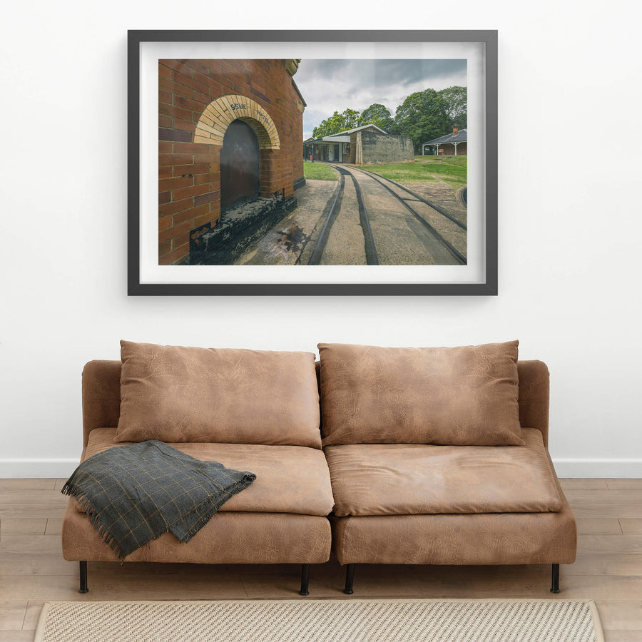 Rails at Newington Armory, narrow-gauge rails curve across a concrete apron, running past the issue hatch of a red brick.
