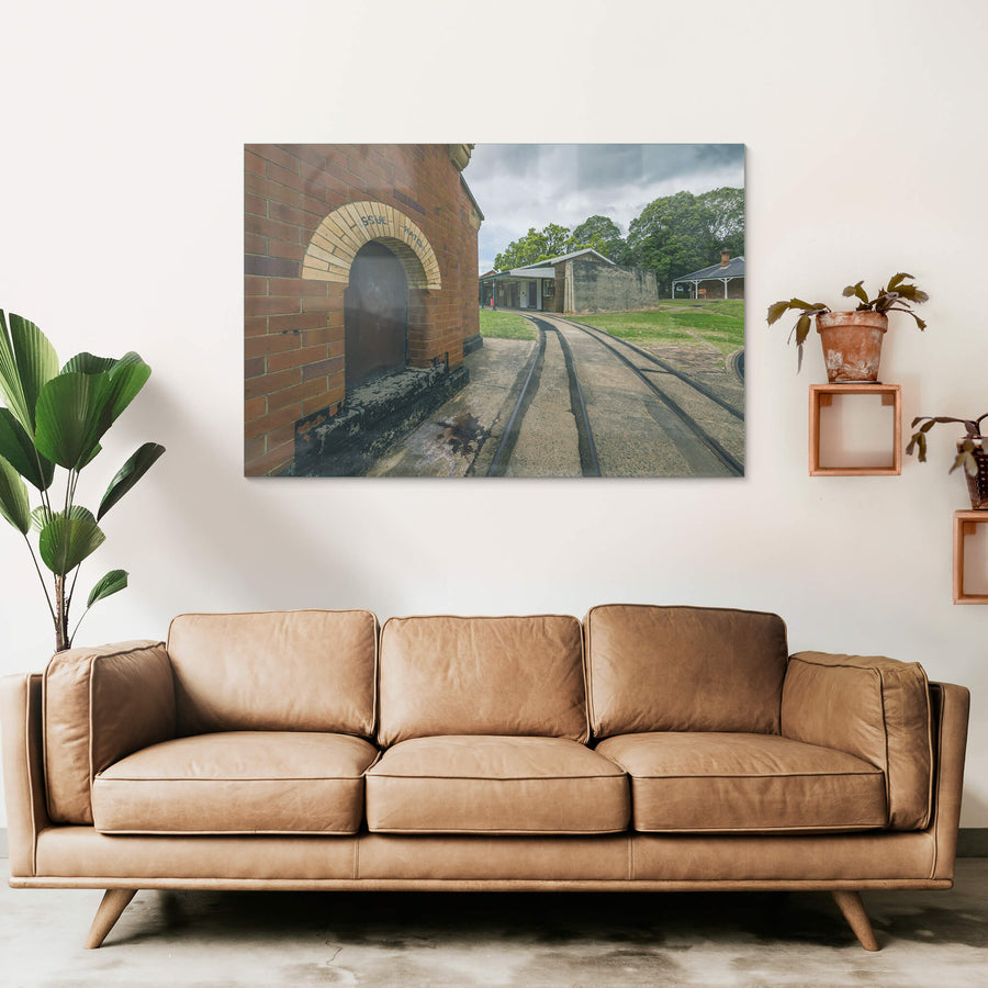 Rails at Newington Armory, narrow-gauge rails curve across a concrete apron, running past the issue hatch of a red brick.