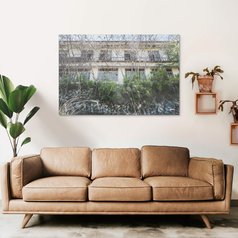 Balcony at Nichitsu Mining Village, a two-storey timber building rises behind a rough stone retaining wall.