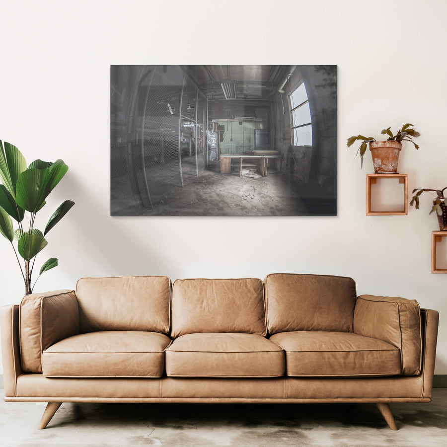 Caged Area at O-I Glass, a wooden desk sits near a large arched window, grey light falling across its surface.