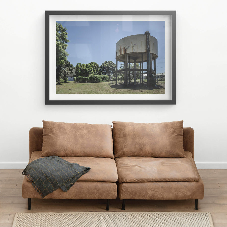 Front Lawn at Peters Ice Cream Factory, a cylindrical steel water tank sits raised on six legs above a mowed front lawn.