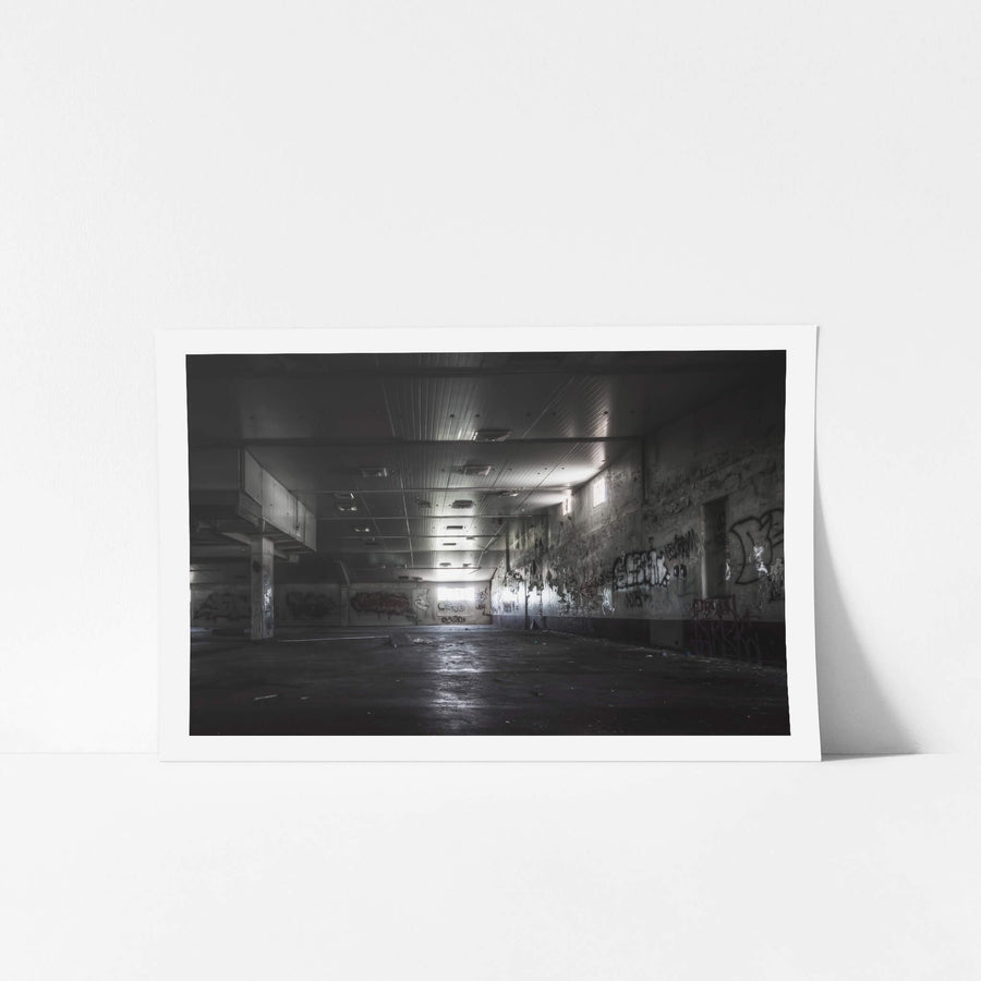 Production Floor at Peters Ice Cream Factory, a wide concrete floor stretches into shadow beneath a corrugated metal ceiling.