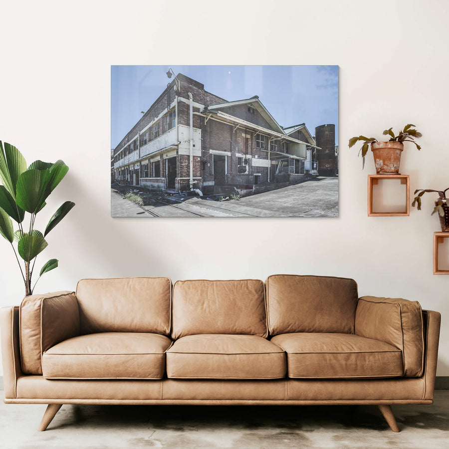 Southeastern Corner at Peters Ice Cream Factory, two storeys of brown brick rise against a flat blue sky.
