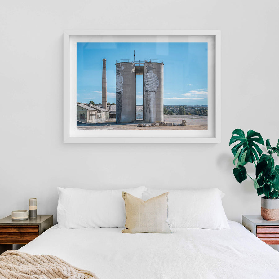 Between Silos at Portland Cement Works, two concrete silos stand side by side on bare ground, a narrow vertical gap cut.