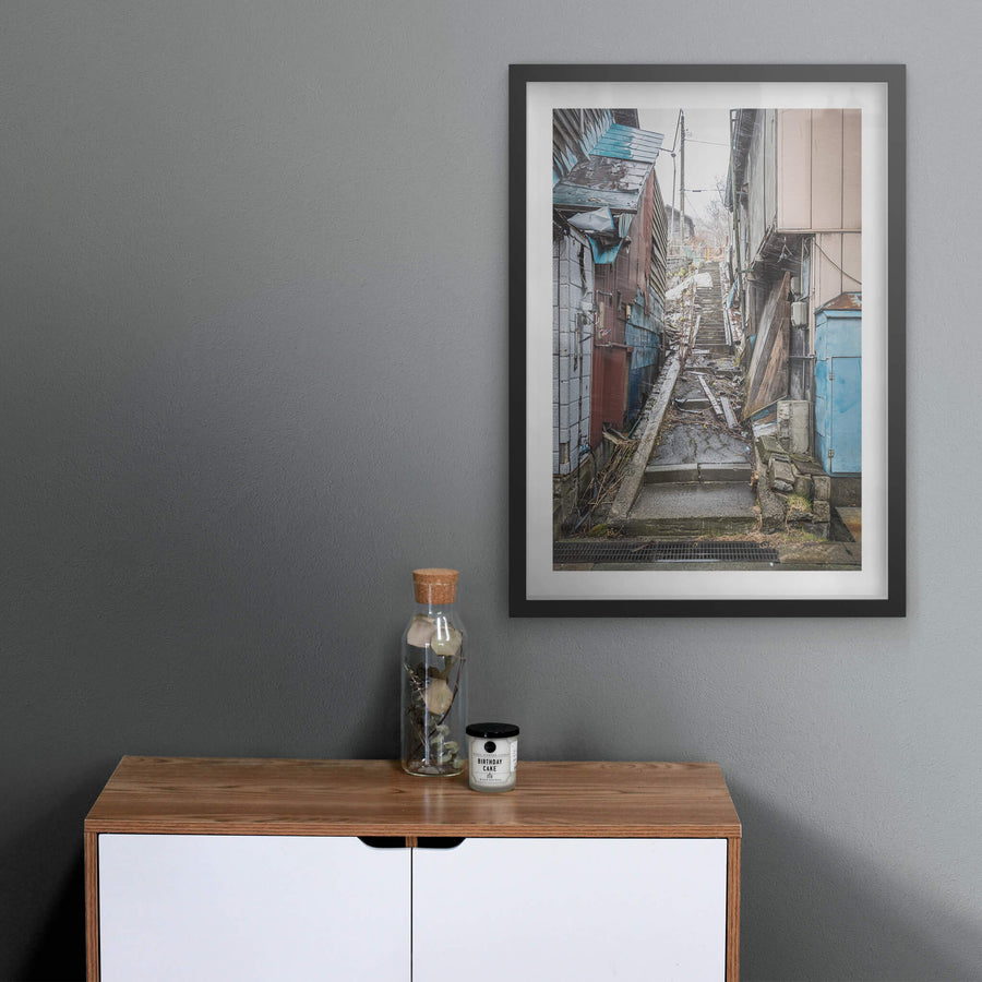 Stairway at Streetscapes of Yubari, a narrow concrete stairway climbs steeply between tightly packed buildings.