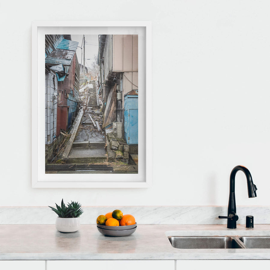 Stairway at Streetscapes of Yubari, a narrow concrete stairway climbs steeply between tightly packed buildings.