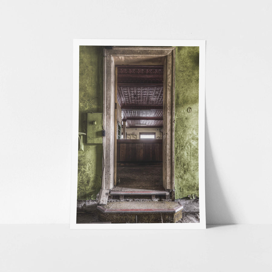 Bar Entrance at Terminus Hotel, a worn step rises to meet the barroom threshold, framed by peeling green paint and chipped.
