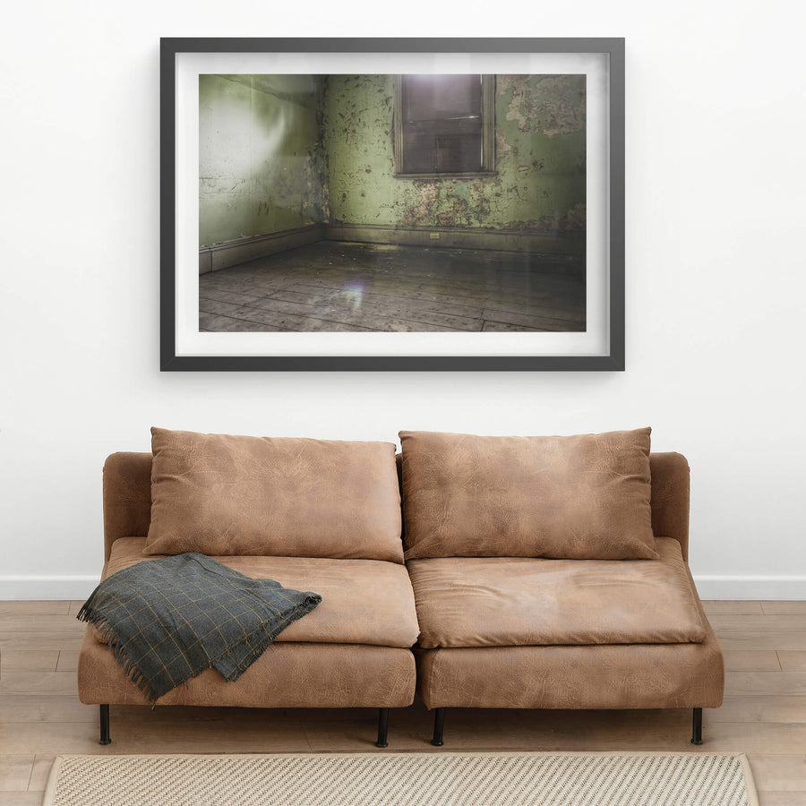 Bare Guest Room at Terminus Hotel, light seeps in through a boarded window, casting a dull glow across the floorboards.
