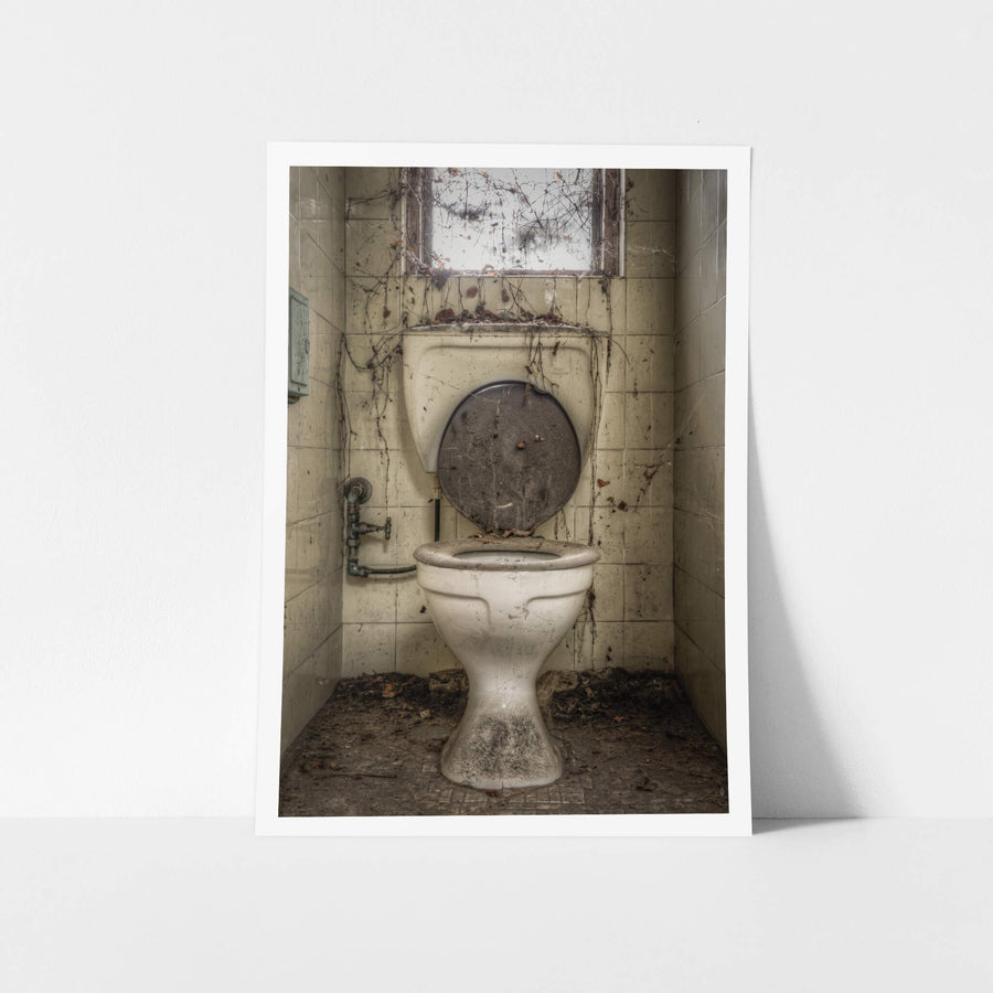 Toilet at Terminus Hotel, a white ceramic pedestal toilet sits centred in a narrow tiled cubicle.