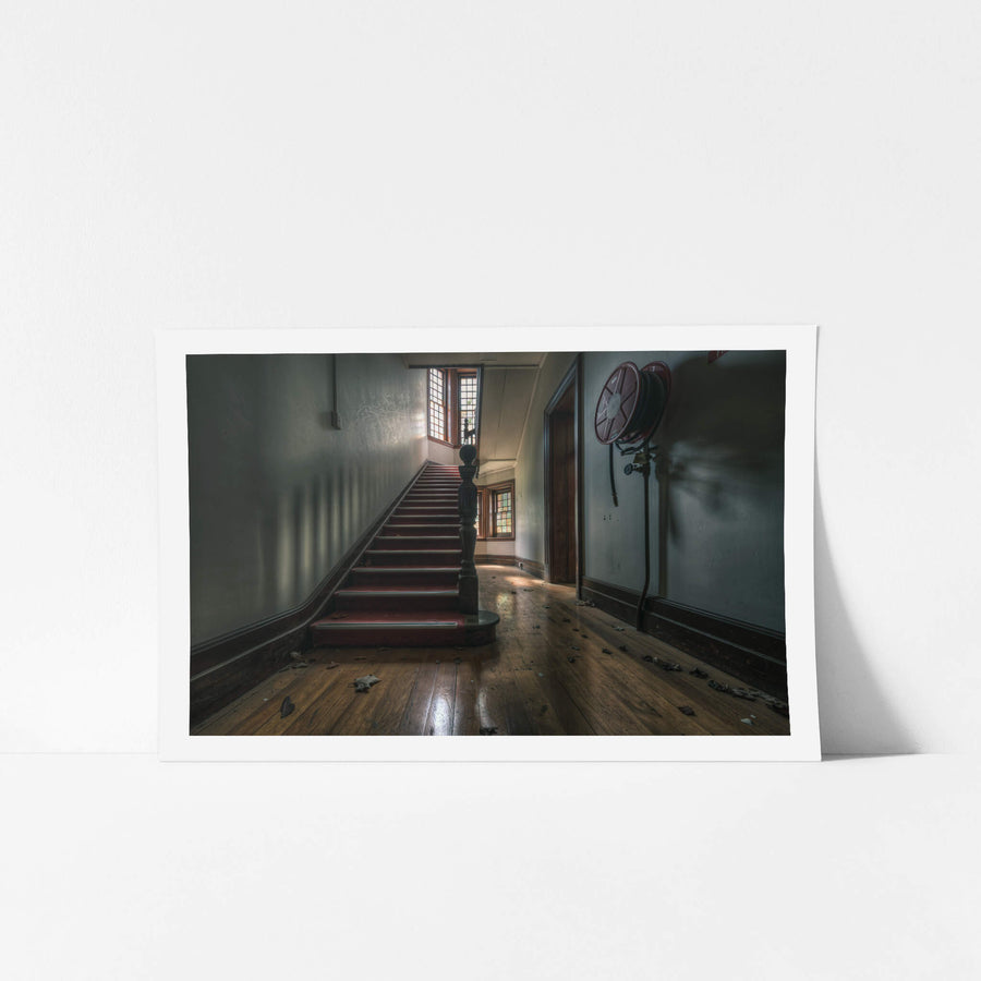 Administration Staircase at The Asylum, a carpeted staircase rises from a ground-floor hallway, its turned newel post.