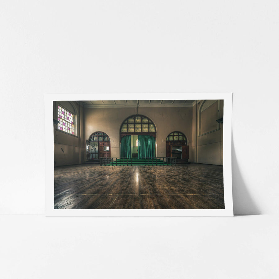 Chapel at The Asylum, a large hall with worn timber floorboards stretching toward a raised stage.