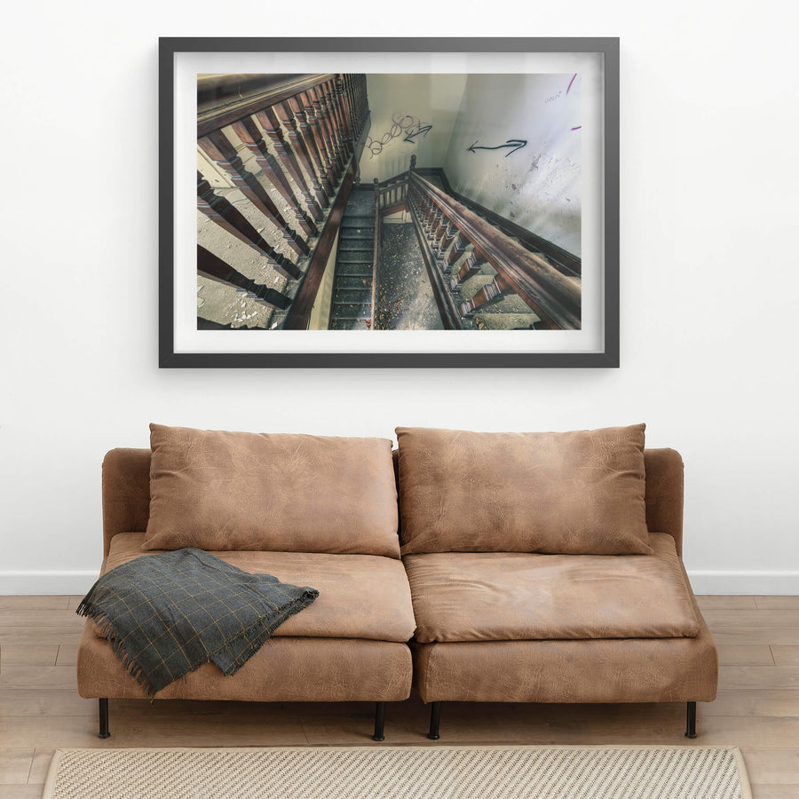 Decayed Stairwell at The Asylum, dark timber balusters run in tight rows down a multi-storey stairwell, their turned.