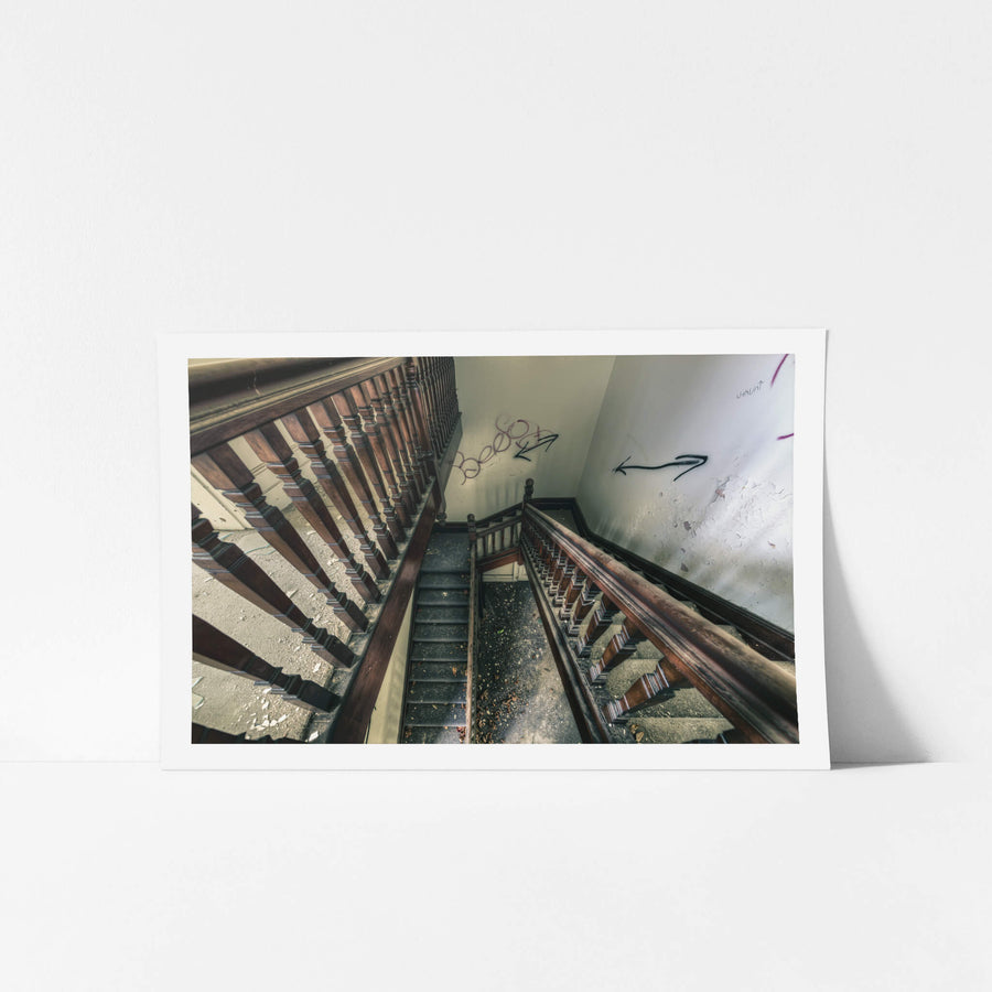 Decayed Stairwell at The Asylum, dark timber balusters run in tight rows down a multi-storey stairwell, their turned.