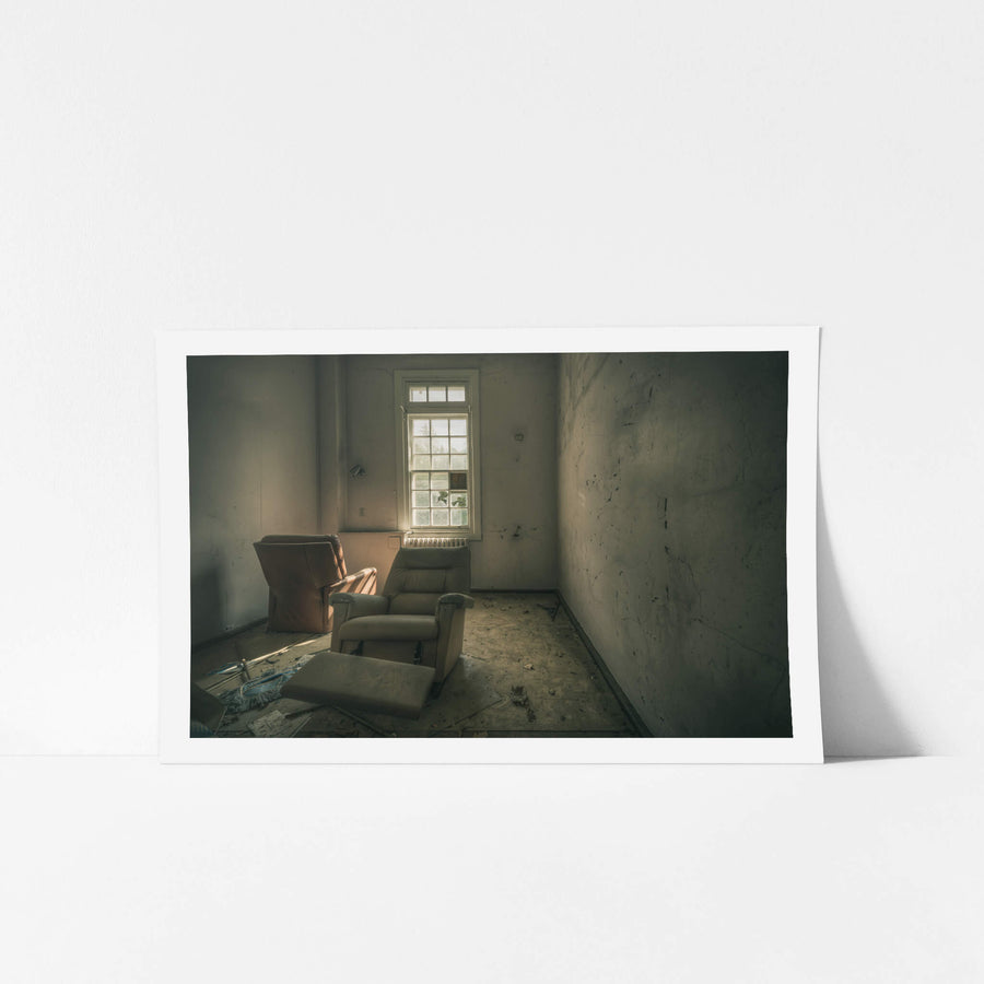 Reflective at The Asylum, two recliner chairs sit angled toward a tall multi-pane window.