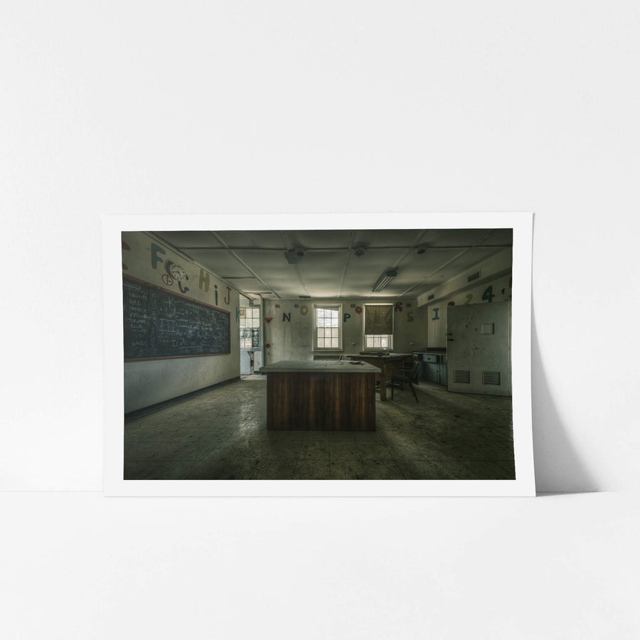 Teaching Table at The Asylum, a heavy timber desk sits at the centre of a disused classroom.