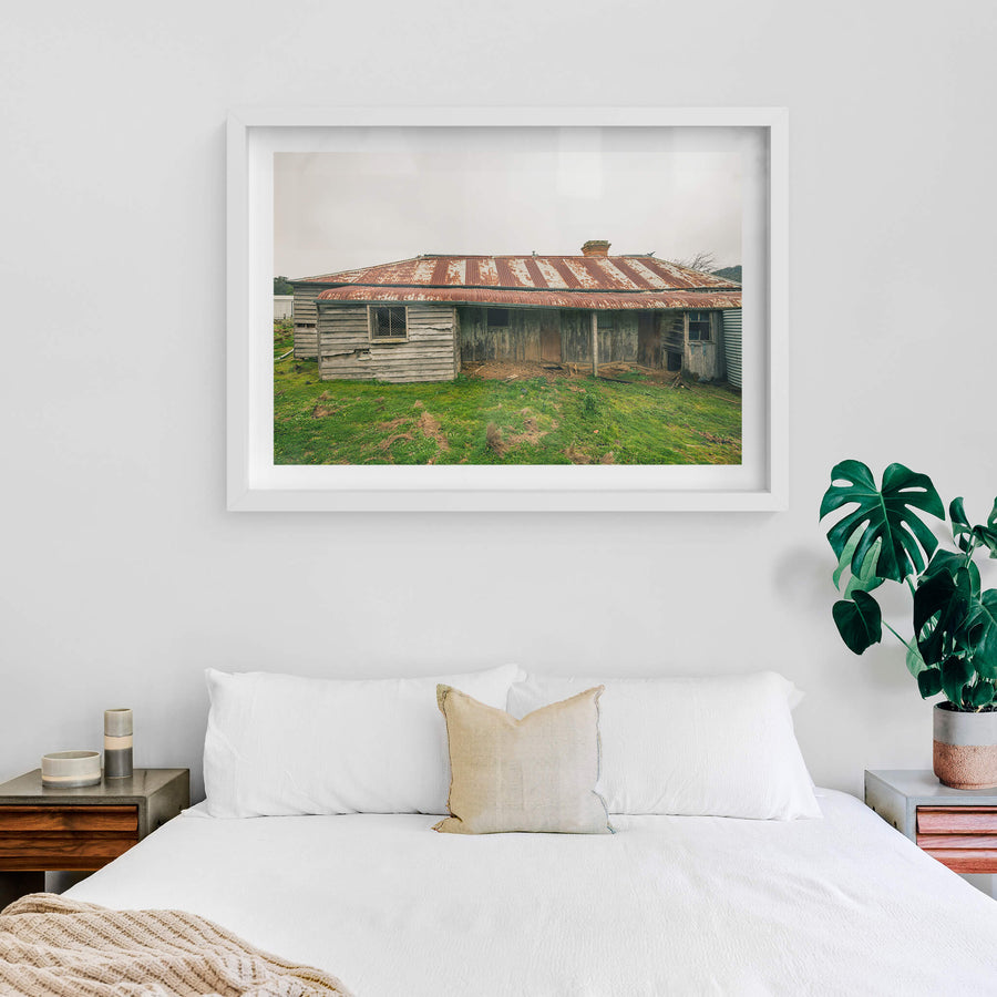 Front Yard at The Post Office, a low-slung timber homestead sits under a corrugated iron roof mottled with rust.