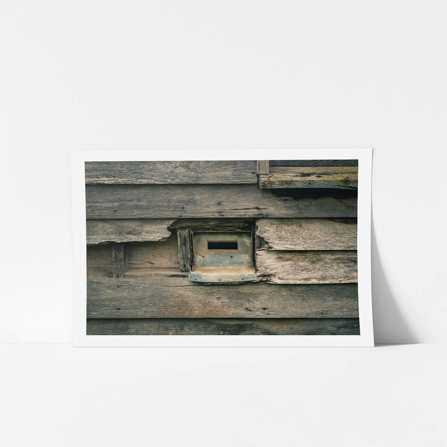 Mail Slot at The Post Office, a galvanised letter slot sits cut into weatherboard cladding, its narrow mouth open.