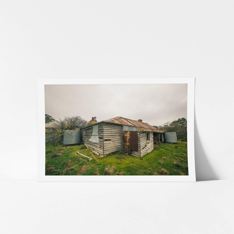 Postmasters Corner at The Post Office, weathered hardwood clapboards, grey and splintered, wrap a low cottage.