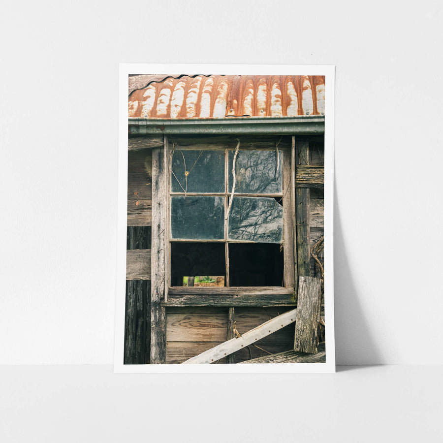 Window Panes at The Post Office, a six-pane timber window set into weatherboard cladding, grey and split with age.