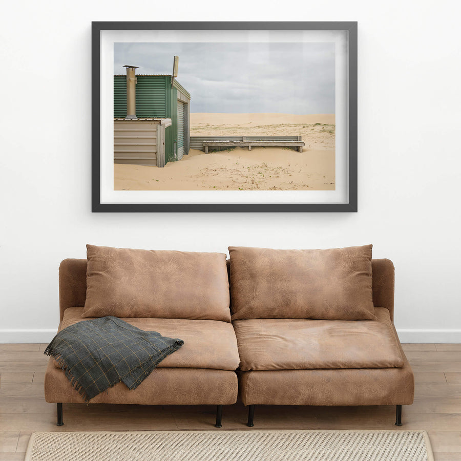 Boardwalk at Tin City, a corrugated iron shack sits half-buried in sand.