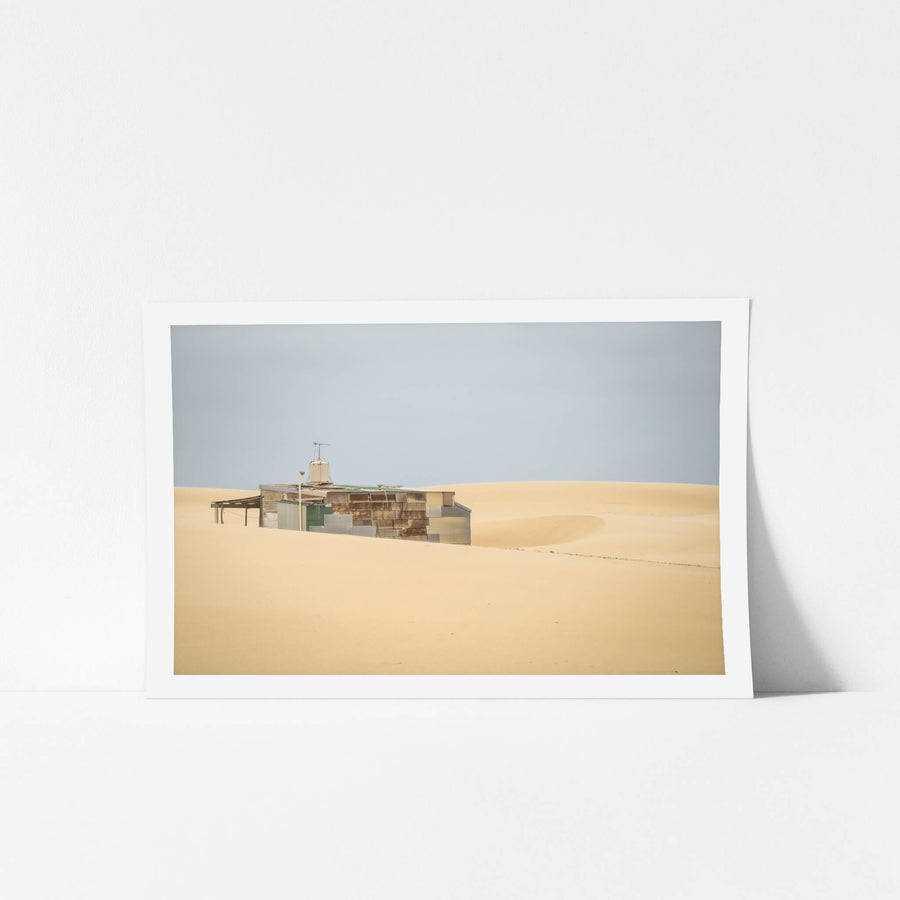 Buried at Tin City, a Tin City shack, recessed in rolling dunes of sand.
