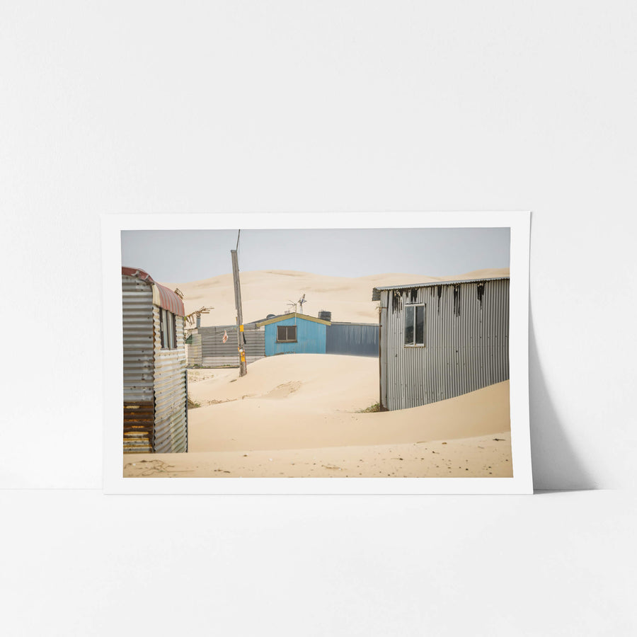 City Centre at Tin City, sand drifts between corrugated iron shacks, banking against walls in smooth curves.