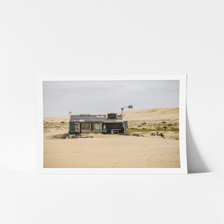 Filthy Phills Ranch at Tin City, sand drifts against the base of a low shack built from corrugated iron, timber cladding.