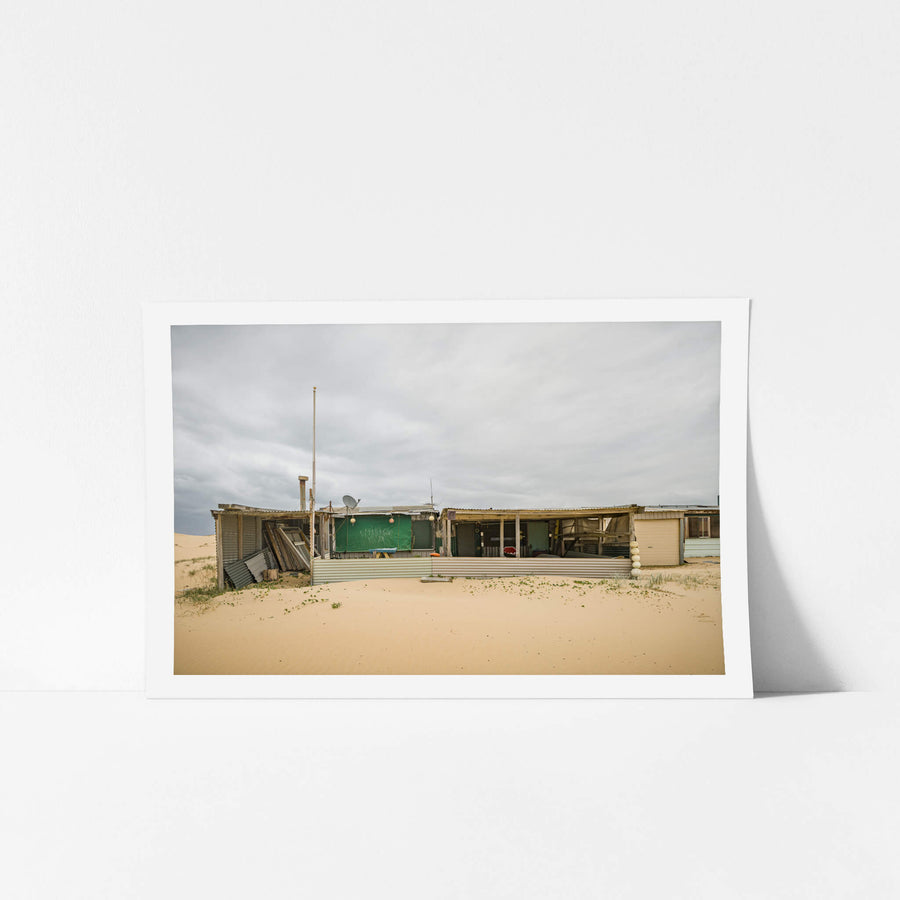 Nine at Tin City, corrugated iron and shade cloth hold together a low sprawl of shack against the dunes.