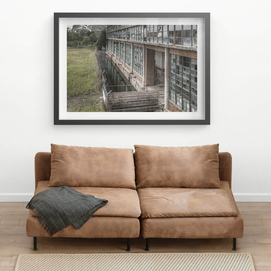 Outlet Canal at Wangi Power Station, brown brick and steel-framed windows rise two storeys above, nearly every pane.