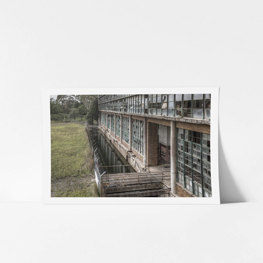 Outlet Canal at Wangi Power Station, brown brick and steel-framed windows rise two storeys above, nearly every pane.