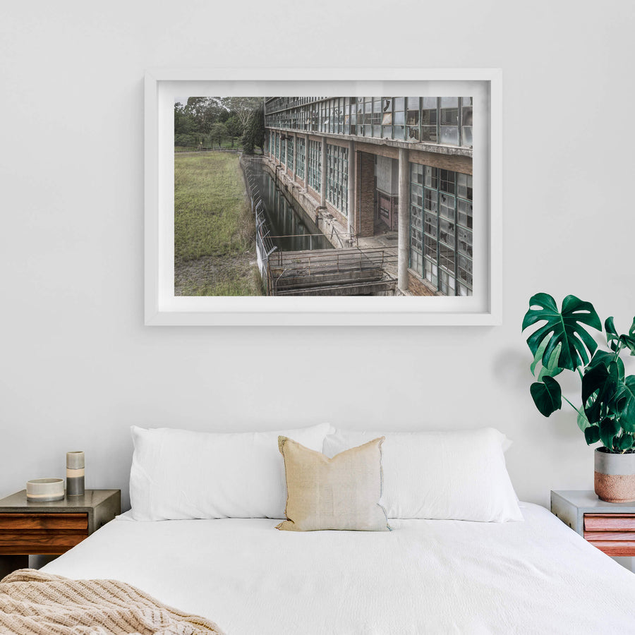 Outlet Canal at Wangi Power Station, brown brick and steel-framed windows rise two storeys above, nearly every pane.