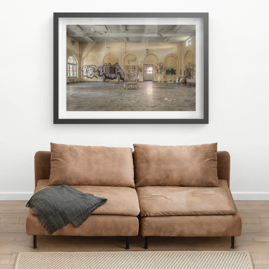 Lone Chair at Waterfall Sanatorium, a floral armchair sits alone at the centre of a large hall.